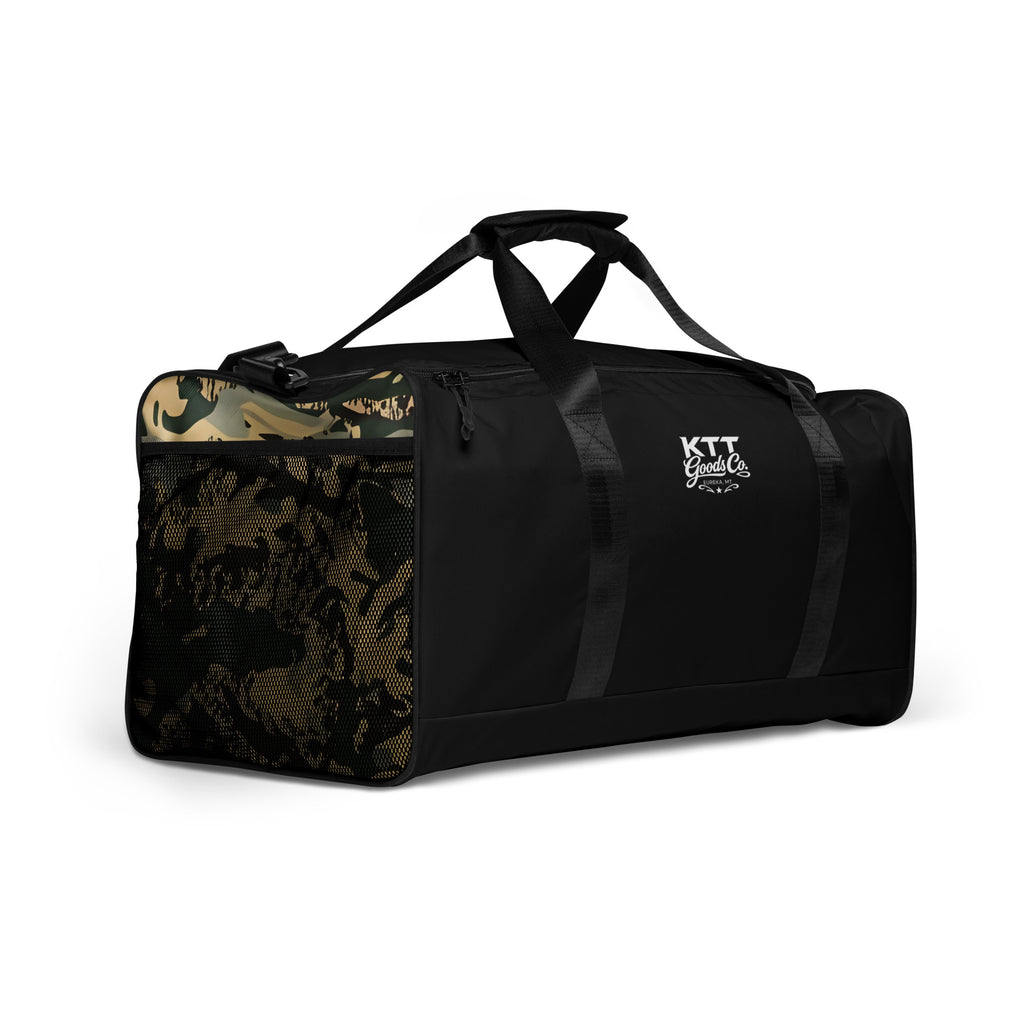 Right-front view of the TV-D1 Field Duffle Bag showing the single white KTT Goods Co. mark and a TV-D1 camouflage side panel.