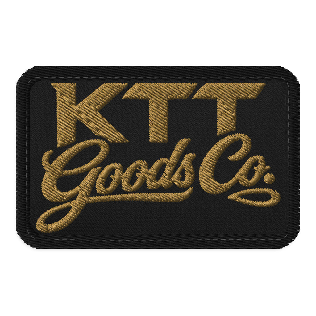 Front view of the KTT Goods Co. Old Gold embroidered wordmark on a black 3.5 × 2.25 in hook-and-loop patch with black edge