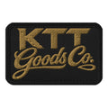 Front view of the KTT Goods Co. Old Gold embroidered wordmark on a black 3.5 × 2.25 in hook-and-loop patch with black edge
